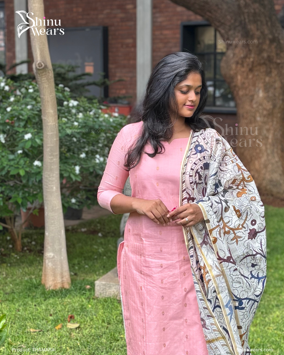 Woman in a pink traditional outfit with a patterned shawl outdoors.